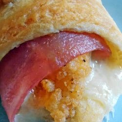 A plate of golden-brown Chicken Cordon Bleu Crescents, made with crescent roll dough, filled with chicken fingers, ham, and swiss cheese, baked to perfection. A delicious and easy meal or appetizer option.