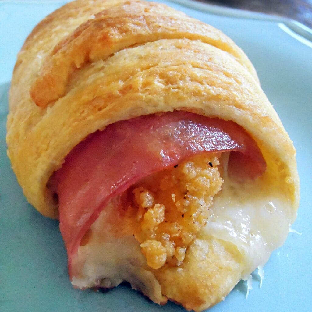 Chicken Cordon Bleu Crescents - Flaky crescent roll dough wrapped around chicken tenders, ham, and Swiss cheese, baked to a golden-brown finish. A mouthwatering and convenient meal or appetizer.